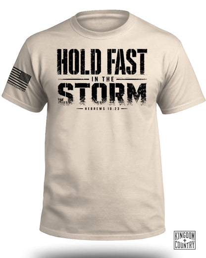 Tan t-shirt with black text reads "HOLD FAST IN THE STORM HEBREWS 10:23".
