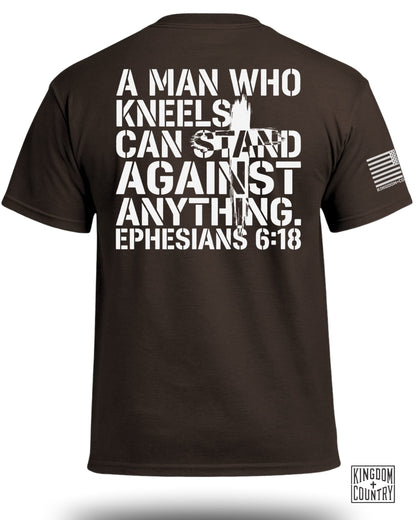 Brown t-shirt with white text: "A MAN WHO KNEELS CAN STAND AGAINST ANYTHING. EPHESIANS 6:18".