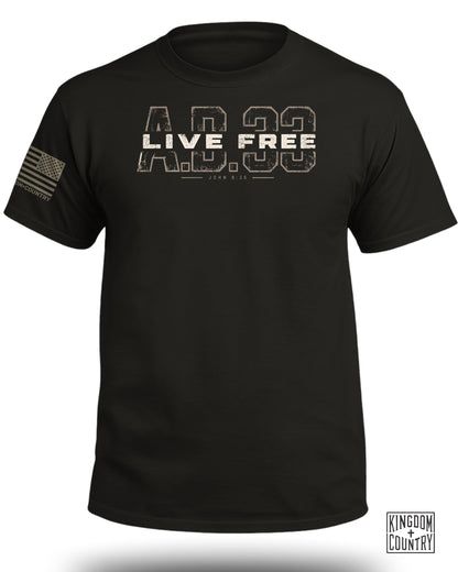A black crewneck t-shirt featuring a distressed A.D. 33 Live Free graphic with John 8:36 on the chest and an American flag on the left sleeve.