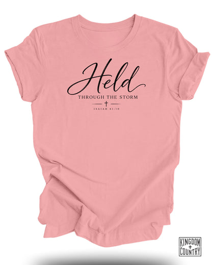 Pink t-shirt with "Held Through The Storm Isaiah 41:10" text.