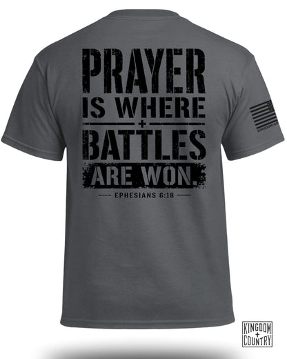 Dark grey t-shirt with black text: "PRAYER IS WHERE BATTLES ARE WON. EPHESIANS 6:18".