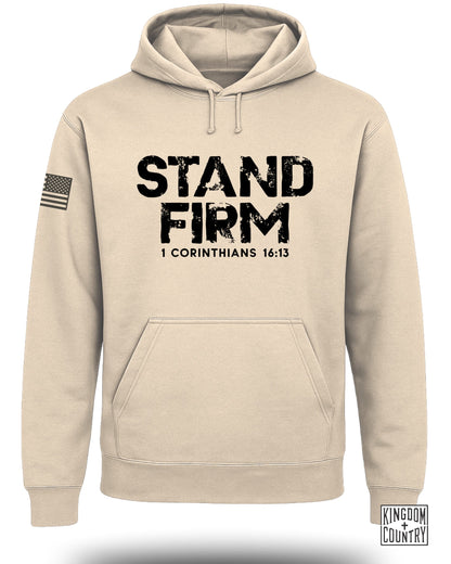Tan hoodie with "STAND FIRM 1 CORINTHIANS 16:13" text and American flag sleeve detail.