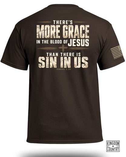 Brown t-shirt viewed from the back, featuring distressed religious text and a small flag on the sleeve.