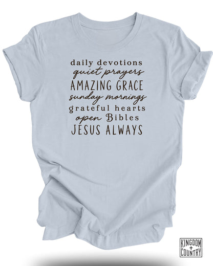 Light blue t-shirt with black text: daily devotions, quiet prayers, amazing grace, sunday mornings, grateful hearts, open bibles, Jesus always.