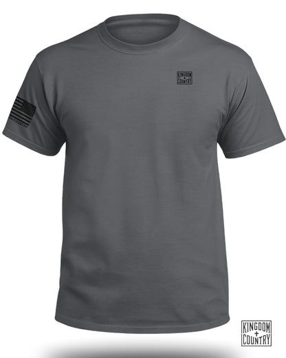 Dark grey t-shirt with a black American flag on the left sleeve and a black logo on the chest.