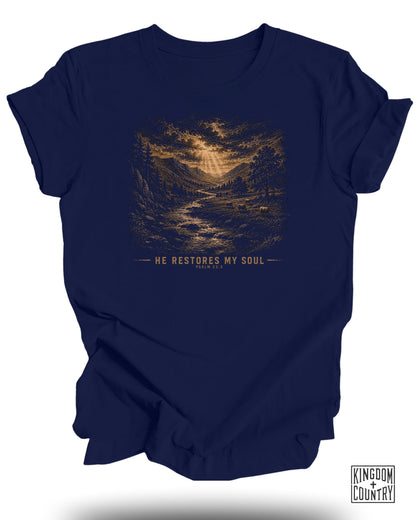 Navy t-shirt with landscape graphic and text "HE RESTORES MY SOUL PSALM 23:3".