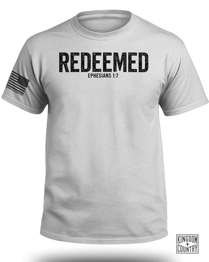 White t-shirt with "REDEEMED EPHESIANS 1:7" text and an American flag detail.