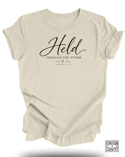 Cream t-shirt with "Held Through The Storm" and Isaiah 41:10.