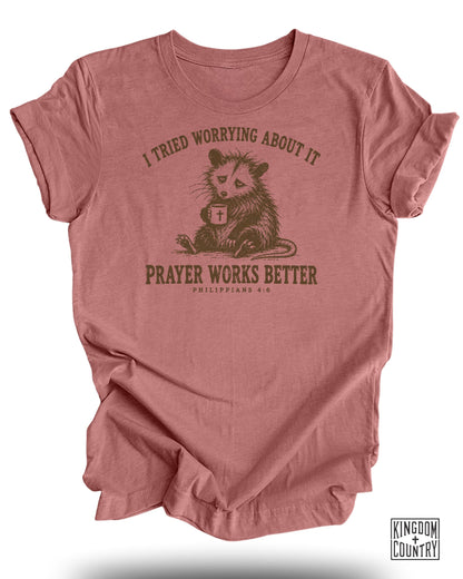 T-shirt with opossum holding mug and text "I tried worrying about it. Prayer works better."