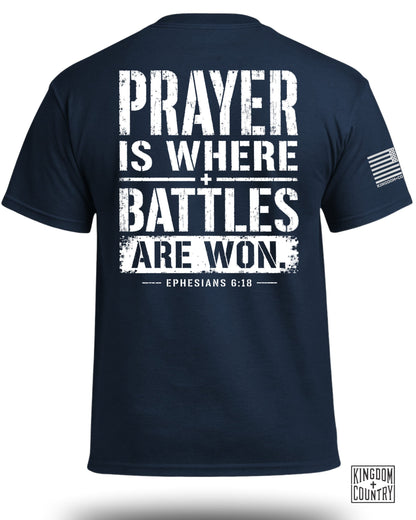 Navy t-shirt with white text "PRAYER IS WHERE BATTLES ARE WON. EPHESIANS 6:18".