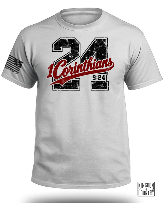White t-shirt with "24 Corinthians 9:24" graphic and American flag sleeve detail.