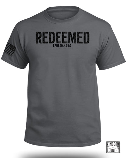 Dark grey t-shirt with black distressed text "REDEEMED EPHESIANS 1:7" and U.S. flag graphic.