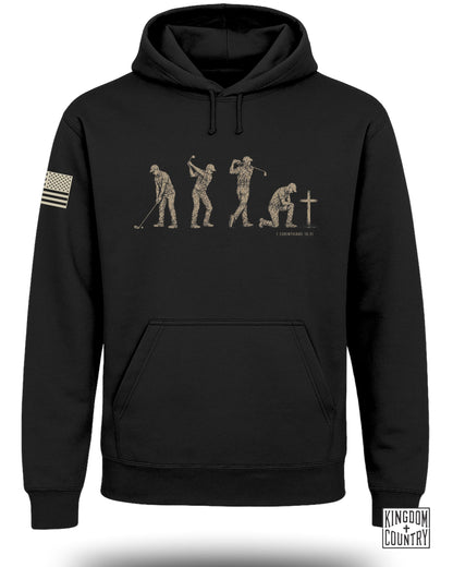 Black hoodie with golf evolution graphic and "1 Corinthians 10:31" text.