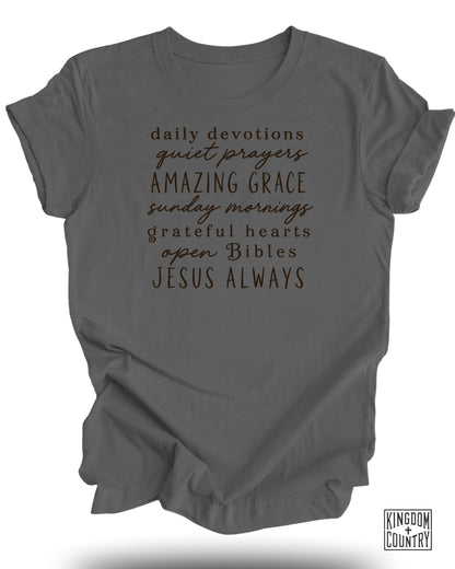 Gray t-shirt with "Daily Devotions Quiet Prayers Amazing Grace Sunday Mornings Grateful Hearts Open Bibles Jesus Always" text.