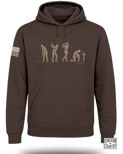Brown hoodie with a graphic of evolving golfers and "1 Corinthians 10:31" text.