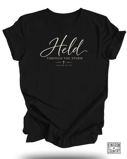Black t-shirt with "Held Through the Storm" and "Isaiah 41:10" text.