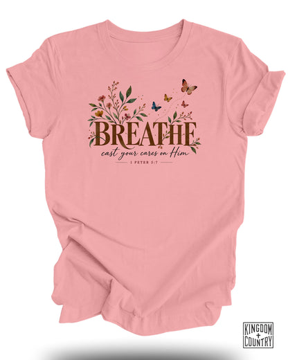 Pink t-shirt with "BREATHE cast your cares on Him" and "1 Peter 5:7" text, floral accents, and butterflies.