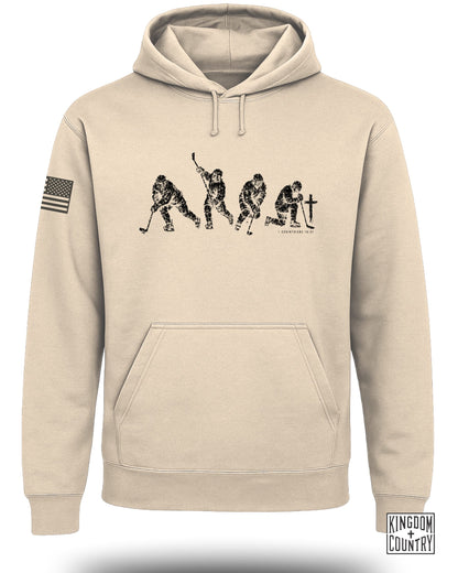 Tan hoodie with black graphic of four hockey players and text "1 CORINTHIANS 10:31".