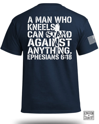 Navy t-shirt with white text: "A MAN WHO KNEELS CAN STAND AGAINST ANYTHING. EPHESIANS 6:18"
