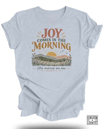 Light blue t-shirt with "Joy Comes in the Morning" and "His Mercies are New" text and sunrise scene.