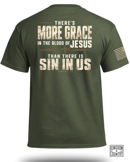 Olive green crewneck t-shirt viewed from the back, featuring distressed religious text and a small flag on the sleeve.